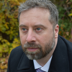 Matthew Zeller: headshot of a middle aged man with a beard in a dark coat